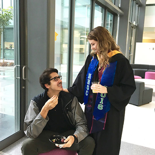 Two students smiling at each other in commencement robe